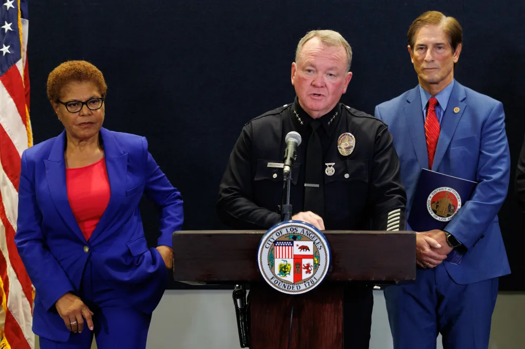 LAPD Police Chief Jim McDonnell speaks at a press conference, flanked by two officials.