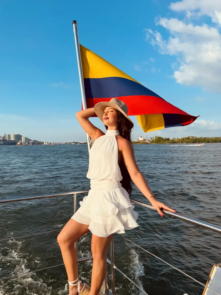 Wendy Duran poses on a boat in front of the Colombian flag.