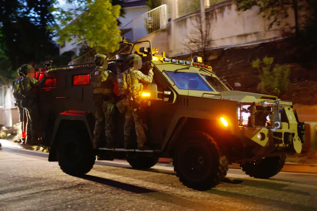 FBI agents in tactical gear stand on an armored vehicle during a nighttime raid outside a home in Tarzana, California.