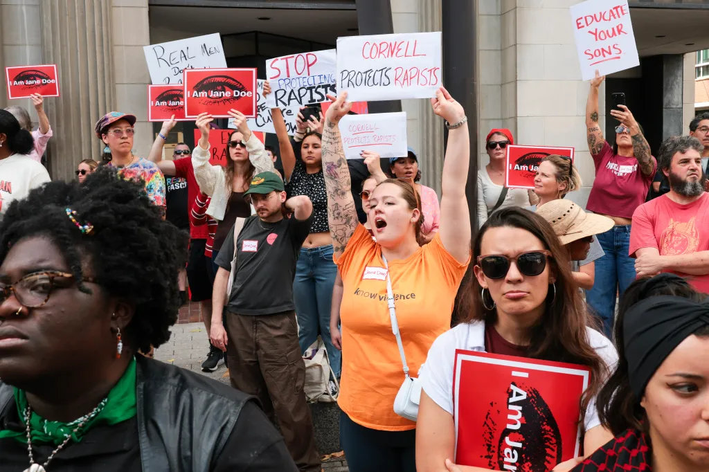 Protesters hold signs demanding answers regarding Cornell University's handling of sexual assault cases.