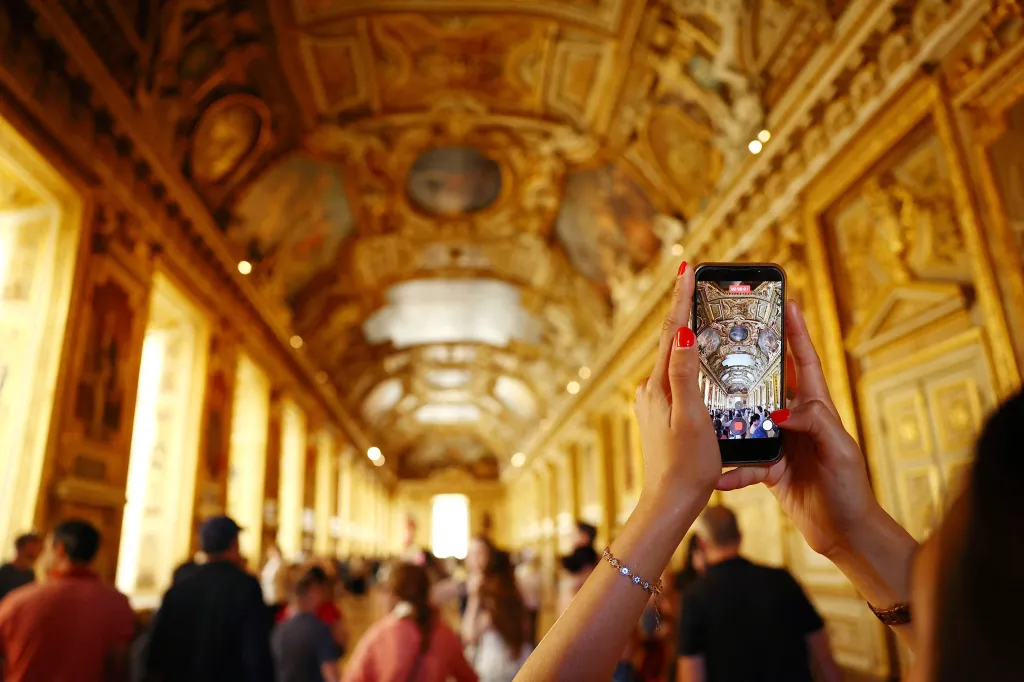 A visitor takes a picture in the Apollo Gallery at the Louvre Museum in Paris as it reopens to the public.