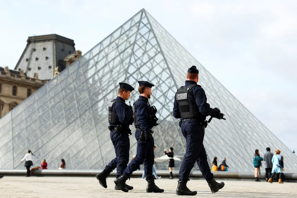 French CRS riot police officers patrol near the glass Pyramid of the Louvre Museum in Paris.