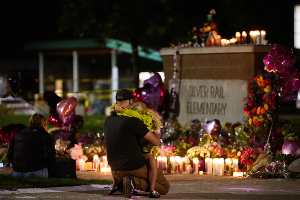 People gather at a memorial outside Silver Rail Elementary School in memory of victims killed in a shooting.