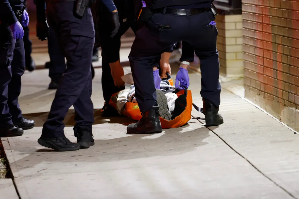Police officers assisting a wounded victim on a stretcher outside a building in the Bronx.