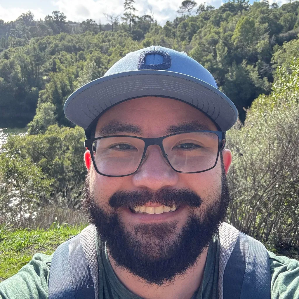 Jonathan McKinsey smiling outdoors with a cap and glasses.