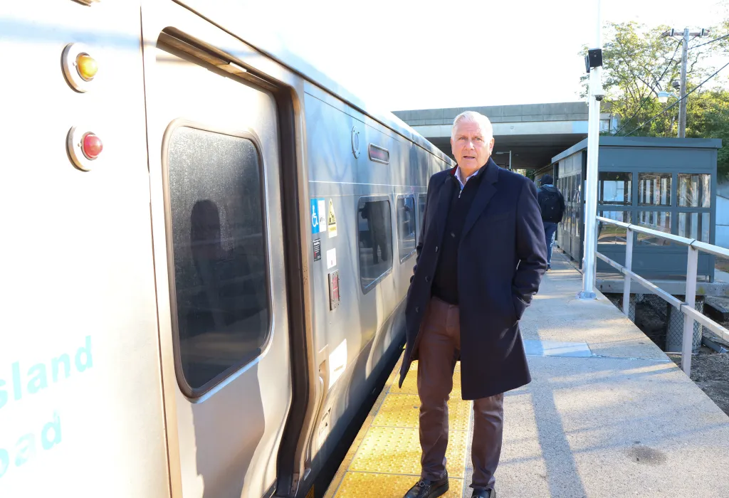 Bruce Blakeman standing on the LIRR station platform next to a train.